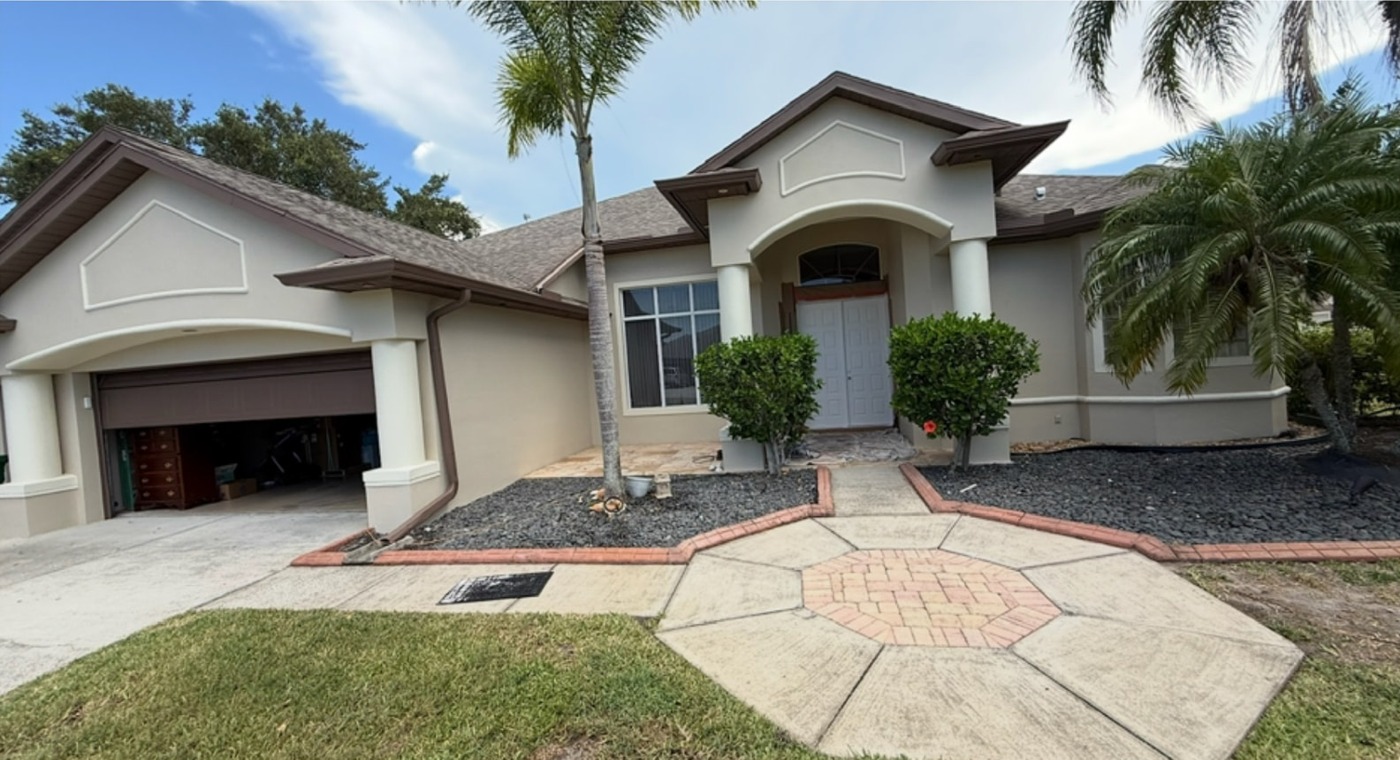 Stucco home repainted in a light neutral color with dark contrasting trim