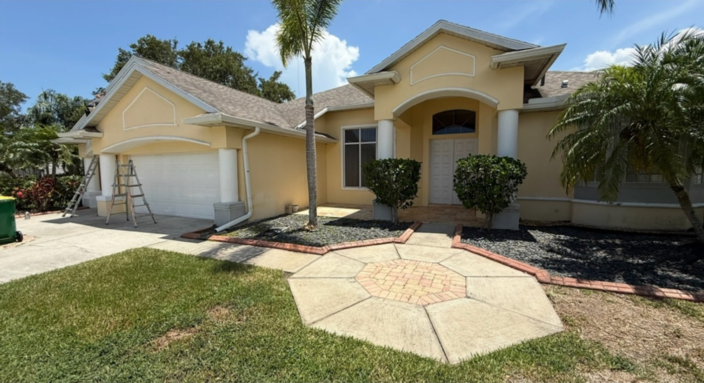 Yellow stucco home with white trim before exterior painting